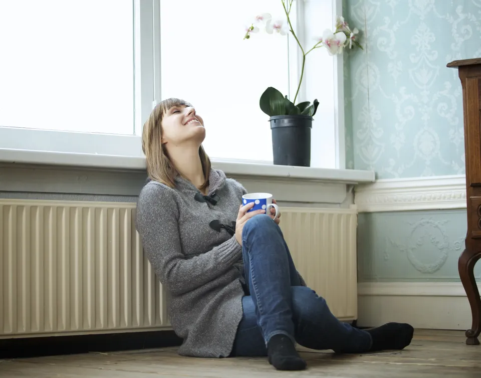 Vrouw verwarmt zich bij radiator